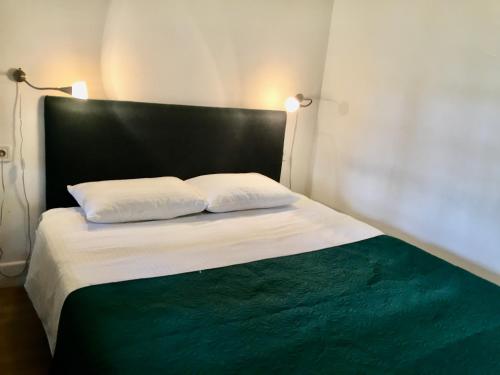 1 cama con 2 almohadas blancas y cabecero negro en The White Loft, en Tiflis