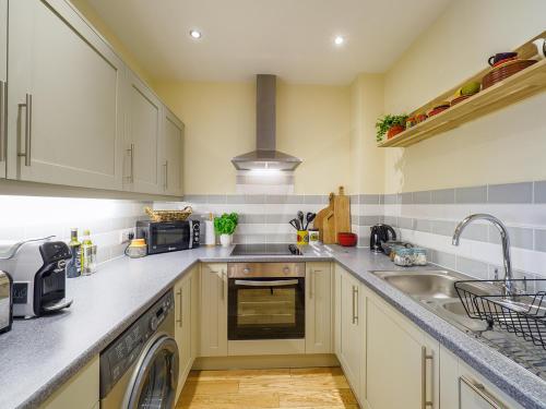 a kitchen with a sink and a dishwasher at 2 Brocklehurst Cottages in Buxton