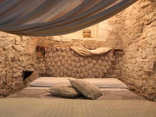 a bedroom with a bed in a stone wall at Trulli Aria di Casa in Alberobello