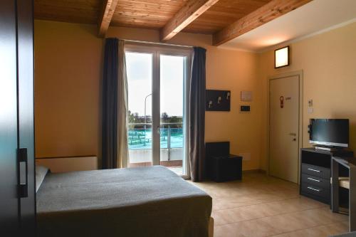 een slaapkamer met een bed en uitzicht op een zwembad bij Hotel Residence Le Dune breakfast included in Lido Adriano
