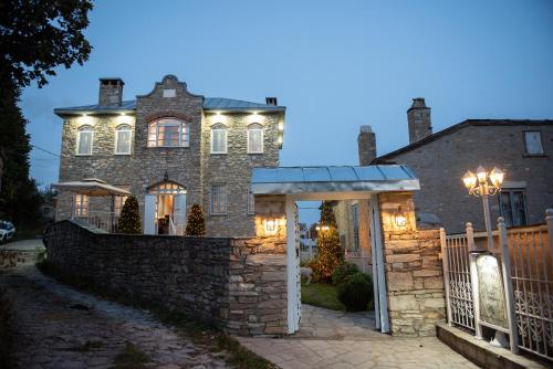a house with a stone fence and lights on it at Dandy Villas Nymfaio - Snow Fairy - Sauna in Nimfaíon