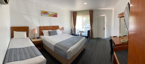 Habitación de hotel con 2 camas y escritorio en Swaggers Motor Inn, en Yass