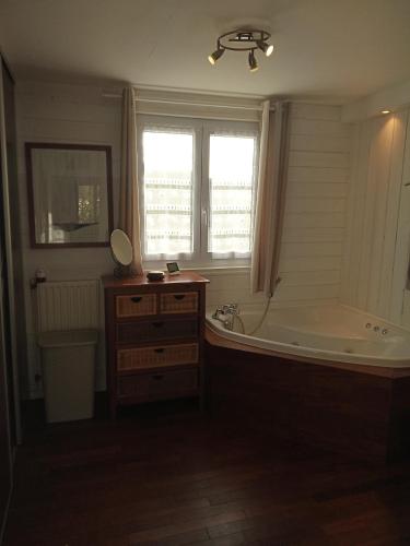 une salle de bain avec une baignoire, un lavabo et un miroir dans l'établissement Gîte de Eric et Rose, à Bernières-sur-Mer