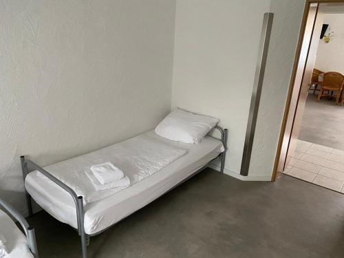 ein kleines Krankenhausbett in einer Ecke eines Zimmers in der Unterkunft H2 in Affoldern