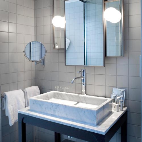 La salle de bains est pourvue d'un grand lavabo en marbre et de miroirs. dans l'établissement Hotel Saint Dominique, à Paris
