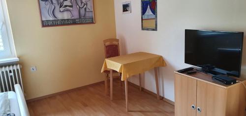 a room with a small table and a television at Gästehaus Eissler in Helmsheim