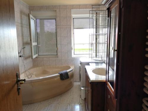ein Bad mit einer Badewanne, einem Waschbecken und einem Fenster in der Unterkunft Pension Nordseebriese in Dornum
