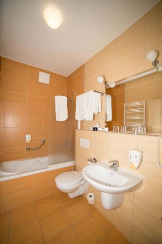a bathroom with a sink and a toilet and a tub at Termálhotel Martfű in Martfů