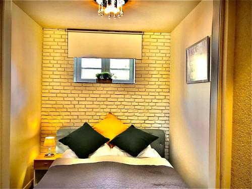 ein kleines Schlafzimmer mit einem Bett mit gelben und grünen Kissen in der Unterkunft Apartament Blue Crystal in Jelenia Góra
