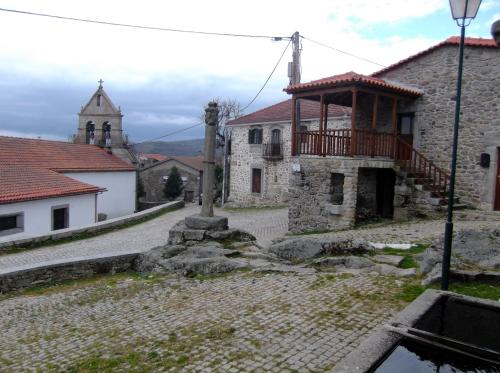 an old stone building with a balcony and a church at Casa do Pelourinho in Rebordainhos