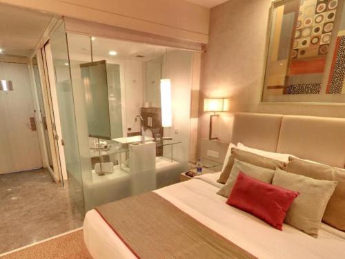 法里達巴德的住宿－法里達巴德麗亭酒店，一间卧室配有一张带红色枕头的大床