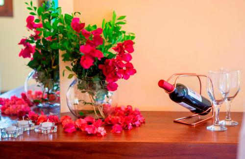 a table with red flowers and a bottle of wine at BELLA VISTA Village in Arraial d'Ajuda