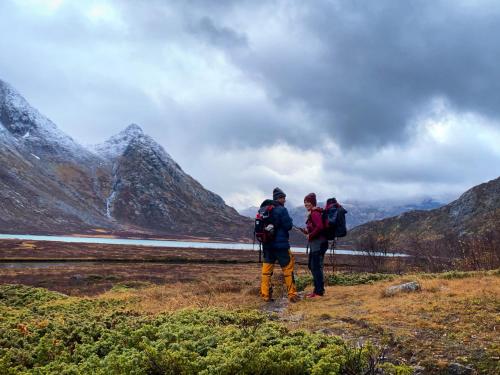 two people walking on a hill with mountains in the background at Lemonsjøen-Jotunheimen-Besseggen in Stuttgongfossen