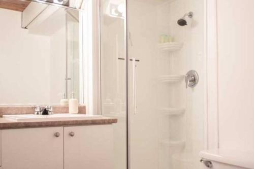 a white bathroom with a shower and a sink at Chalet Mont Sainte-Anne in Beaupré