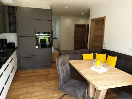 a kitchen and dining room with a wooden table and yellow pillows at Golf & Ski Appartements Mittersill Trausmuth Monika inkl Sommercard - Golfplatz 500 m entfernt, inkl Waschmaschine, Trockner in Mittersill