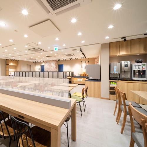 a cafeteria with tables and chairs and a kitchen at Super Hotel Sendai Hirose Dori in Sendai