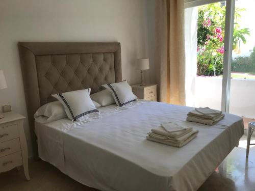 1 dormitorio con 1 cama grande y toallas. en Apartment Costalita, direct beach access, ground floor, salt water pool, en Estepona