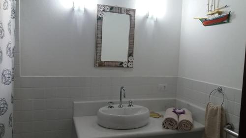 a white bathroom with a sink and a mirror at Bangalôs Parque Verde in Paraty