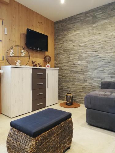 - un salon avec un canapé et une télévision sur un mur en briques dans l'établissement la Télécabine studio 4 personnes, à Marnaz