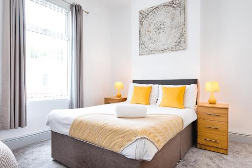 a bedroom with a large bed with yellow pillows at Work Stay - 3BR - Near Stadium - Smart TVs in Swansea