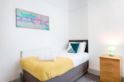 a bedroom with a bed with a yellow blanket at Work Stay - 3BR - Near Stadium - Smart TVs in Swansea