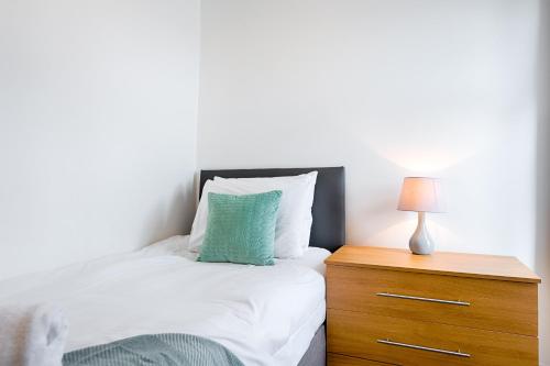 a bedroom with a bed and a nightstand with a green pillow at Work Stay - 3BR - Near Stadium - Smart TVs in Swansea