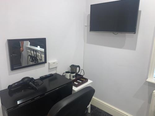 a desk with a chair and a television on a wall at Addison House in Woking