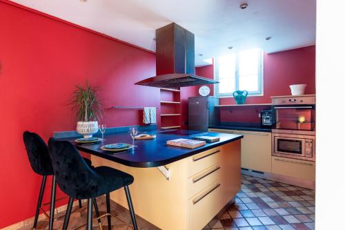une cuisine aux murs rouges et un comptoir avec des chaises dans l'établissement PLACE DU PALAIS DES PAPES 3 chambres Parking Climatisation 3 Salles de bain, à Avignon