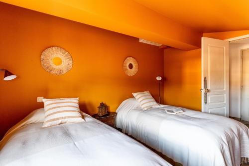 2 Betten in einem Zimmer mit orangefarbenen Wänden in der Unterkunft PLACE DU PALAIS DES PAPES 3 chambres Parking Climatisation 3 Salles de bain in Avignon