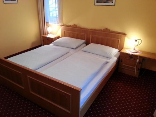 2 Betten in einem kleinen Zimmer mit zwei Lampen auf beiden Seiten in der Unterkunft Gasthof Zur Post in Bad Goisern