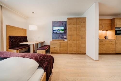 a bedroom with a bed and a table and a kitchen at Alpina Wagrain in Wagrain