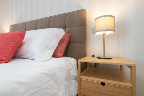a bed with a lamp on a night stand next to it at 9 Quartos Alojamento in Avelar