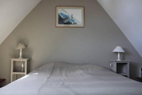 ein weißes Schlafzimmer mit einem Bett mit einem Bild an der Wand in der Unterkunft La Petite Maison in Trégastel