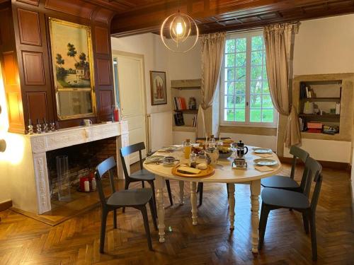 a dining room with a table and chairs and a fireplace at Le Jardin dans les vignes in Barsac