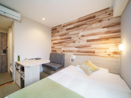 a bedroom with a wooden accent wall and a bed and a desk at Super Hotel Sendai Hirose Dori in Sendai
