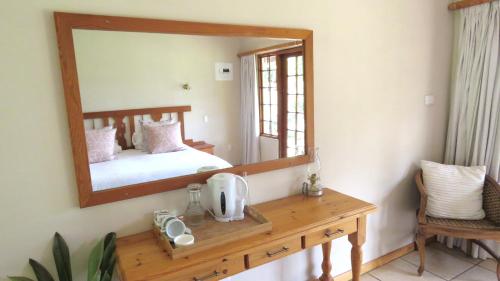 a mirror in a room with a bed and a wooden table at Old Inchgarth Farmstay in Himeville