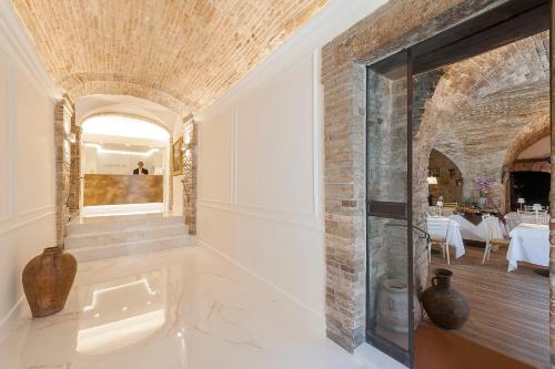una grande camera con una parete di mattoni e una porta di vetro di Asisium Boutique Hotel ad Assisi