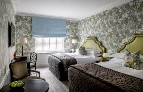 a hotel room with two beds and a chair at The Kensington Hotel in London