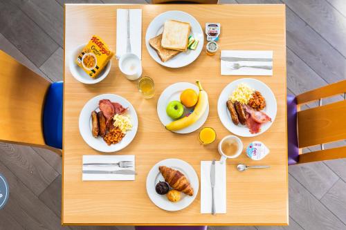 a wooden table with plates of breakfast food on it at Holiday Inn Express Norwich, an IHG Hotel in Norwich