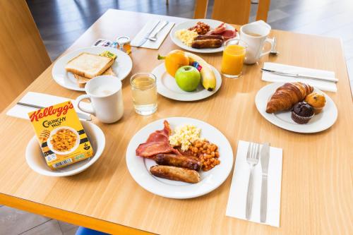 uma mesa de madeira com pratos de comida para o pequeno-almoço em Holiday Inn Express Norwich, an IHG Hotel em Norwich