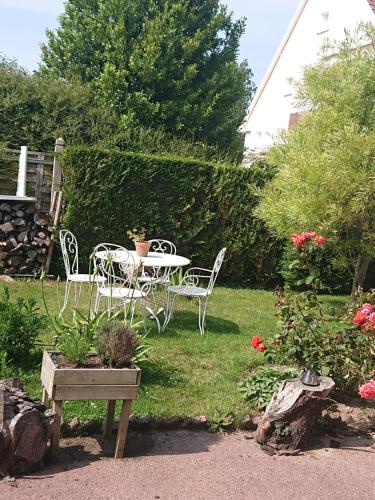 einen Tisch und Stühle in einem Garten mit Blumen in der Unterkunft JOYEUX REVEIL in Courseulles-sur-Mer