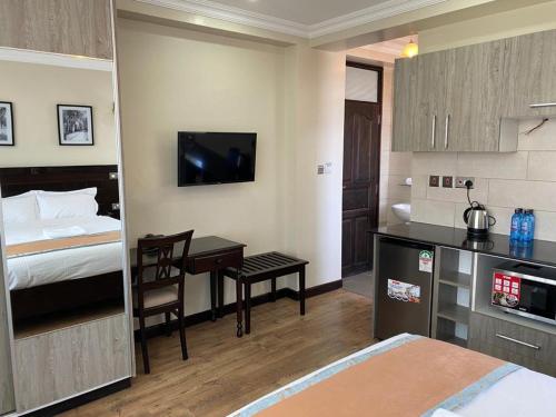 um quarto de hotel com uma cama e uma secretária e um quarto em Hemak Suites em Nairobi