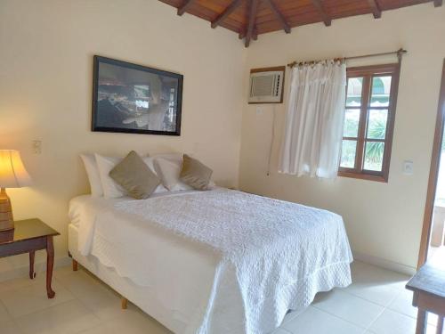a bedroom with a white bed and a window at POUSADA BLUE MOON in Búzios