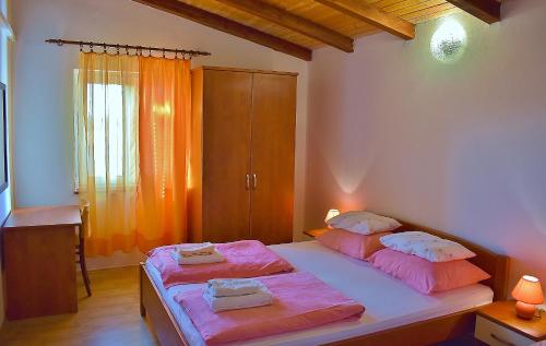 a bedroom with two beds with pink sheets at Feniks Apartmani Lopar in Lopar