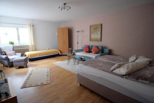 ein Schlafzimmer mit einem Bett, einem Sofa und einem Stuhl in der Unterkunft Ferienwohnung Heinzelmann in Baden-Baden