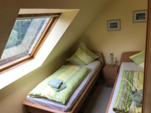 two beds in a small room with a window at Haus Achterum in Langeoog