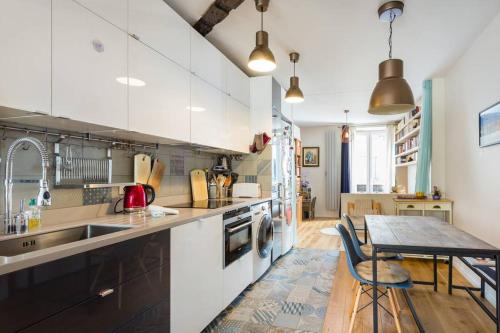 une cuisine avec des armoires blanches et une table en bois dans l'établissement Appartement calme au coeur de Montmartre !, à Paris