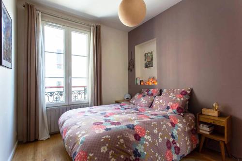 une chambre avec un lit avec une couette colorée et une fenêtre dans l'établissement Appartement calme au coeur de Montmartre !, à Paris