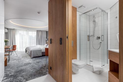 a bathroom with a toilet and a shower and a bed at City Apartments - Młyńska 49 in Koszalin