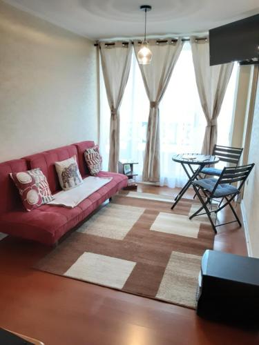 a living room with a red couch and a table at MaranathaAparthotel in Talcahuano
